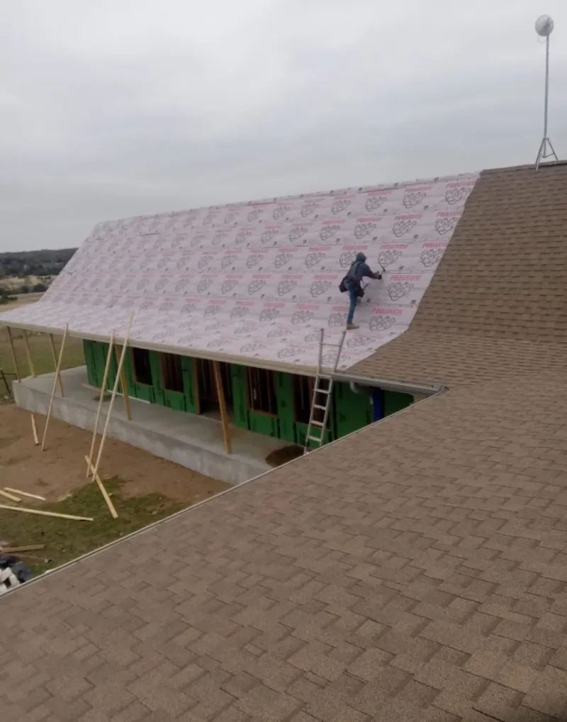 Worker preparing underlayment for a metal roof installation in North Potomac